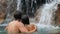 Happy couple bathing by waterfall in embracing and hugging romantic