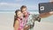 Happy couple on beach taking selfie with smart phone
