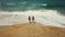 Happy couple carefree running to the water on the beach. Picturesque ocean coast of Portugal