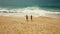 Happy couple carefree running to the water on the beach. Picturesque ocean coast of Portugal