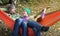 Happy couple chilling in hammock in autumn forest. Woman playing