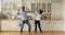 Happy couple dancing in domestic kitchen while listen energetic music