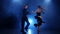 Happy couple dancing jive in smoky studio with blue spotlight