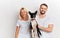 Happy couple with dog posing to the camera isolated over white background