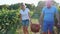 Happy couple of farmers carrying a basket of grape at vineyard