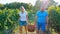 Happy couple of farmers carrying a basket of grape at vineyard