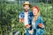 happy couple of farmers holding ripe tomatoes in field at farm and looking