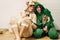 Happy couple in festive funny pajamas hugging their cats and smiling. Celebrating Christmas or New Year eve. Man in deer and woman