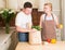 Happy couple with grocery paper bag with vegetables in kitchen.