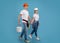 Happy couple in hardhats and safety glasses walking with paint bucket