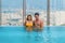 Happy couple have fun together in pool at clubhouse on high rise building