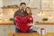 Happy couple holding huge balloon while celebrating Valentine`s Day or having anniversary party