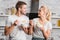 happy couple holding plates and spoons with corn flakes and looking at each other