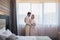 Happy couple in hotel room in the morning. Just married man and woman standing at window