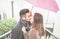 Happy couple kissing under pink umbrella in rainy day outdoor - Handsome lovers having tender moments - Love and relationship