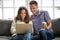 Happy couple laughing looking on laptop screen sitting on sofa