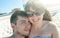 Happy couple in love embracing each other, look at camera and taking selfies. Young man and woman Sitting on beach enjoying