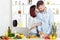 Happy couple in love in kitchen making healthy juice from fresh orange. couple is kissing