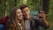 Happy couple in love making selfie on smartphone, making photos during hiking walk in forest, tracking shot, slow motion
