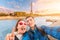 Happy couple in love a man and a woman embrace and take a selfie on the banks of the Seine river with the Eiffel tower in the