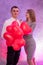 Happy couple in love posing with red air balloons in shape of heart