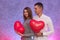 Happy couple in love posing with red air balloons in shape of heart