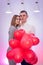 Happy couple in love posing with red air balloons in shape of heart