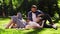 Happy couple in love resting on blanket in park, woman lying on male knees, man feeding her with fresh strawberries