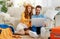 Happy couple with luggage in living room choosing flight via laptop