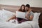 Happy couple lying on a bed with computer - Beautiful married couple watching sex video on laptop laughing together - People,