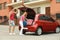 Happy couple near car trunk with suitcases