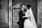 Happy couple of newlyweds kissing in front of old church door b&w