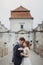 Happy couple of newlyweds posing near castle, fairytale wedding moment beautiful bride and groom hug near ancient castle entrance