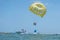 Happy couple Parasailing on Tropical Beach in summer. Couple under parachute hanging mid air. Having fun. Tropical Paradise. Posit