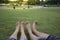 Happy couple relaxing on green grass. Couple lying on grass outdoor. Barefoot. Asian male and female, in a favorite p