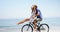 Happy couple riding bicycle at beach