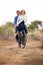 Happy couple riding old bicylce on dirt road