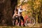 Happy couple riding on retro bicycle against the autumn background trees