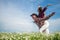 Happy couple running between the grass on a chamomile field in spring, freedom