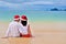 Happy couple in Santa hats relaxing on tropical sandy beach near sea, Christmas and New Year holiday vacation