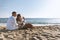 Happy couple seating with champagne on the beach. Summer vacations concept