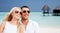 Happy couple in shades over beach with bungalow