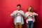 Happy couple showing heart signs, isolated on red