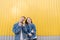 A happy couple shows fingers up against the background of the yellow wall