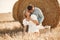 Happy couple sitting on bale in farmland
