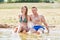 Happy couple sitting on the beach by the sea