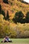 Happy couple sitting on grass against the autumn background trees