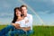 Happy couple sitting on a meadow under rainbow