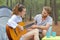 Happy couple sitting near tent with guitar