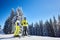 Happy couple skiers posing on skis before skiing at ski resort. Clear blue sky, snow-covered fir trees on background.